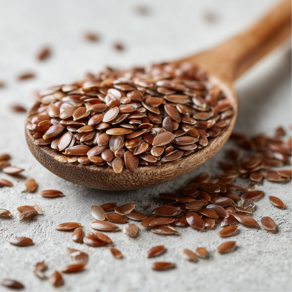 Wooden spoon filled with flaxseeds on a light surface
