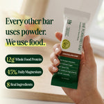 Hand holding a protein bar package with text highlighting features - view 2